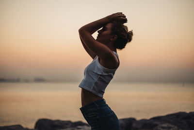 Young woman standing at beach during sunset