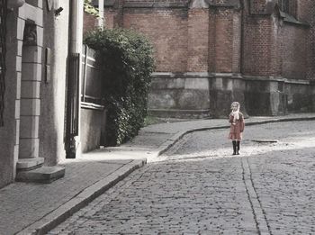 Rear view of woman walking on cobblestone street