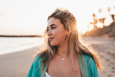 Side view of young woman standing at beach