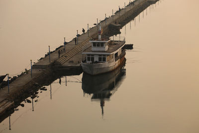 Boat moored in lake against sky during sunset