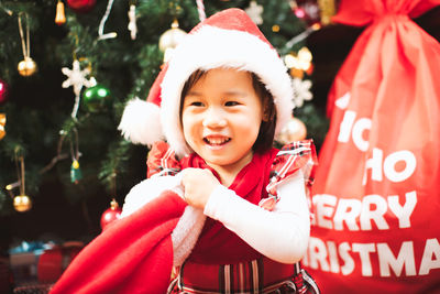 Smiling girl searching for gifts by christmas tree