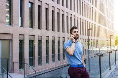 Full length of man standing on mobile phone in city
