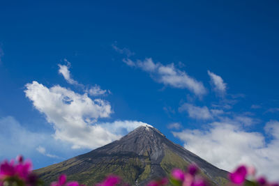 Low angle view of volcanic mountain against blue sky