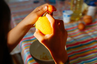 Close-up of child hands grating lemon preparing cake in the kitchen at home