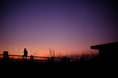 Silhouette woman against orange sky