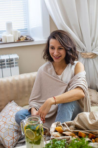 Portrait of smiling young woman sitting at home