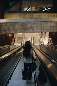 Rear view of woman on escalator