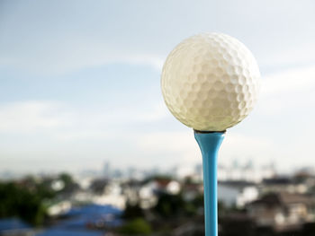 Close-up of golf ball on tee against sky