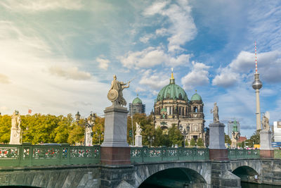 View of arch bridge over building against cloudy sky