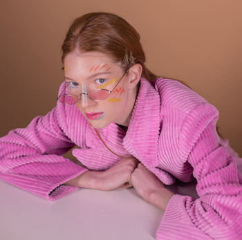 Portrait of girl with painted face sitting against wall