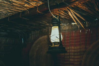 Illuminated lamp hanging on ceiling in hut