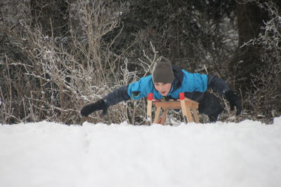 Teenage boy sledding on snow