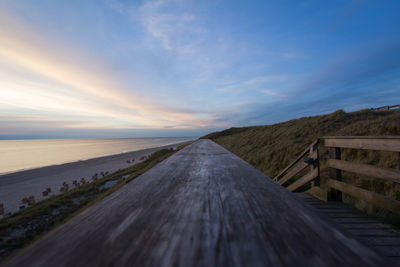 Road by sea against sky during sunset