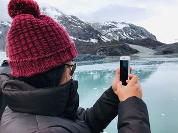 Midsection of person using mobile phone on snowcapped mountain