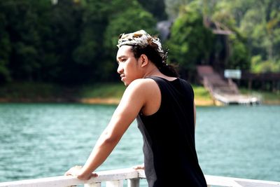 Side view of young woman looking away while standing on lake