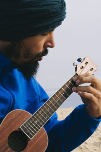 Close-up of man playing ukulele at beach