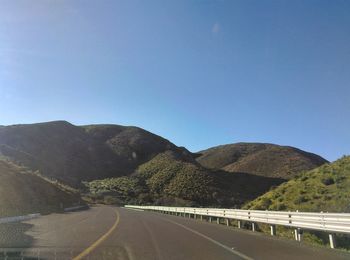 Road leading towards mountains against sky