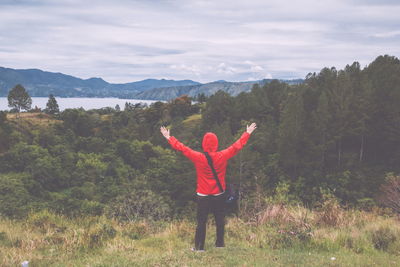 Rear view of man with arms outstretched standing on field