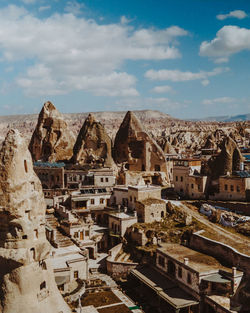 Amazing scenery of massive fairy chimneys and traditional aged houses located in mountainous valley against cloudy blue sky on sunny day in cappadocia turkey