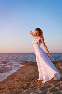 Young adult woman in a white dress on the beach