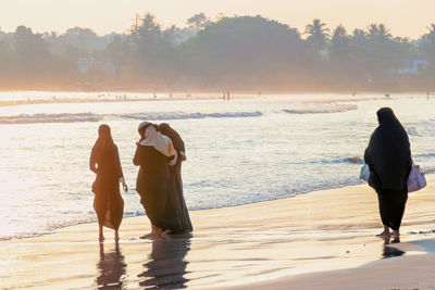 Rear view of women on beach against sea