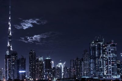 Illuminated cityscape against sky at night