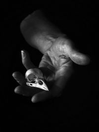Close-up of hand holding toy over black background