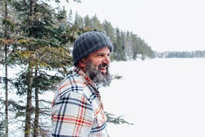 Side view of man standing on snow covered field against sky