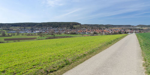 Scenic view of field by houses against sky