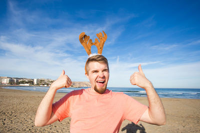 Portrait of happy man at beach against sky