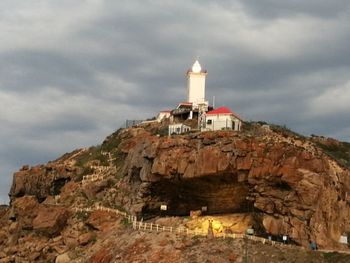 Low angle view of lighthouse on rock against sky