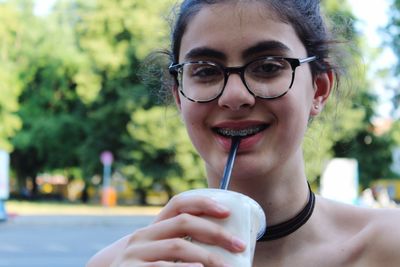 Close-up portrait of a smiling young woman drinking glass