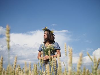 Rear view of woman standing on field against sky