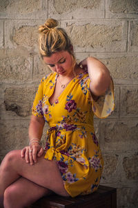 Beautiful young woman sitting on wall