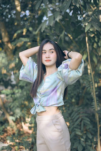 Portrait of a beautiful young woman standing against plants