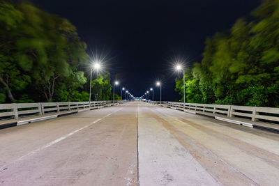 Empty road along trees at night