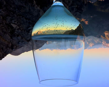 Close-up of glass of water against blue sky