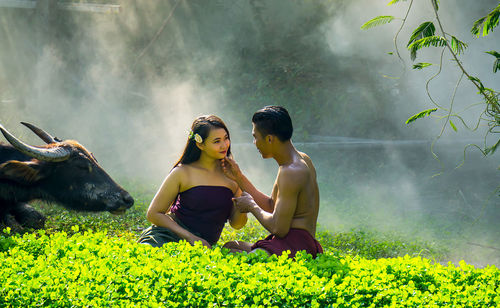 Smiling young couple romancing on grassy field