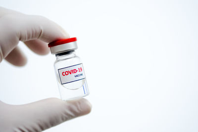 Close-up of hand holding bottle over white background