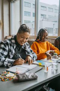 Smiling female students studying together in classroom at community college