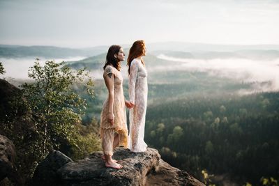 Rear view of women standing on land against sky