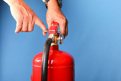 Close-up of hand holding bottle against blue water