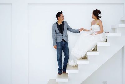 Groom holding hands of bride on steps