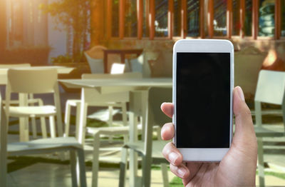 Cropped hand of person using smart phone at sidewalk cafe