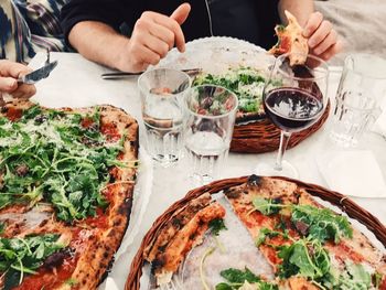 Midsection of person having pizza on table at restaurant