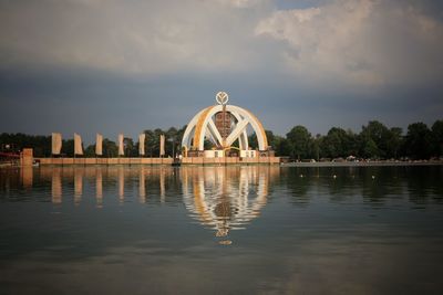 Reflection of building in lake against cloudy sky