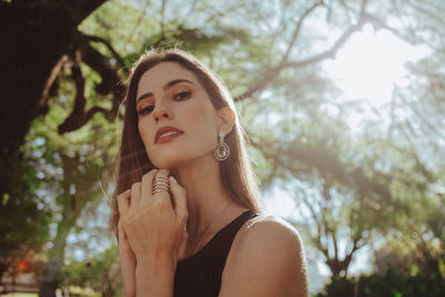 Portrait of beautiful young woman against blurred trees
