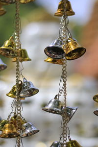 Close-up of small bells hanging against buddha statue