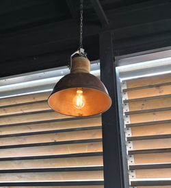 Low angle view of illuminated light bulb hanging from ceiling