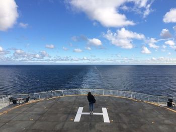 Woman standing at helipad in ship on sea against sky